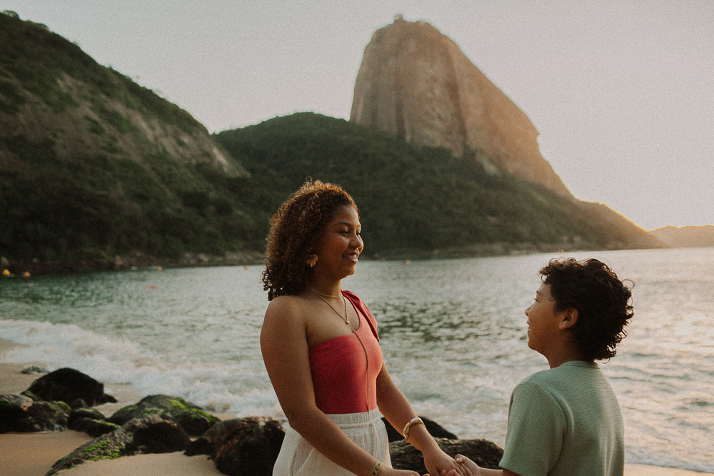 Alice e seu irmão juntos durante ensaio fotográfico de 15 anos na Praia Vermelha, com o Pão de Açúcar ao fundo.
