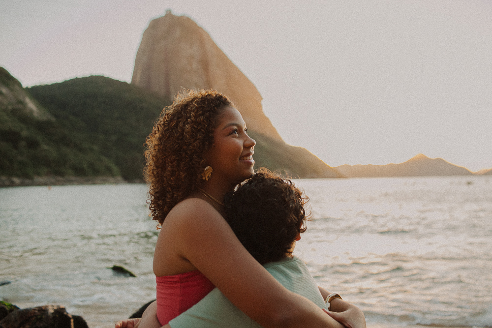 Abraço entre Alice e seu irmão durante ensaio de 15 anos na Praia Vermelha, em um registro espontâneo de carinho entre irmãos.