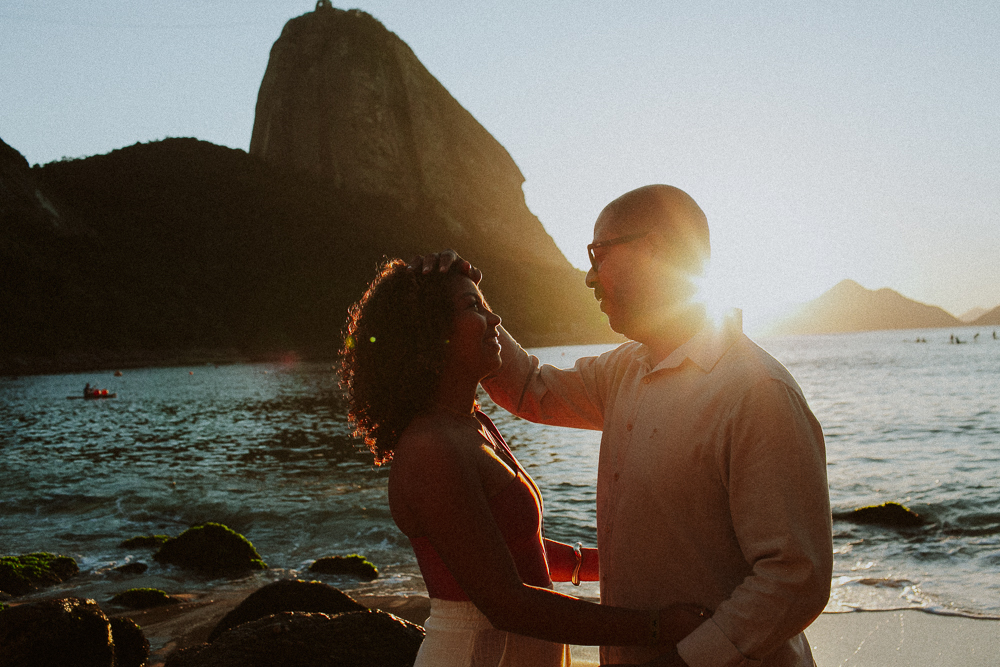 Pai e filha em um momento de conexão durante ensaio fotográfico de 15 anos na Praia Vermelha, Rio de Janeiro.