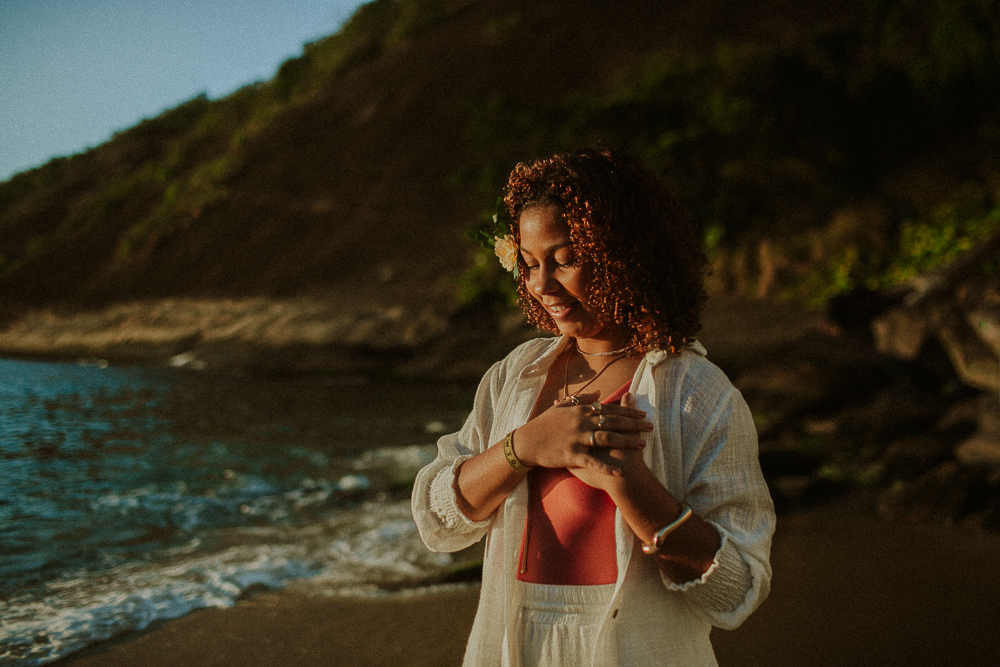 Alice sorrindo e segurando uma flor durante ensaio de 15 anos na Praia Vermelha, em um retrato espontâneo e afetivo.