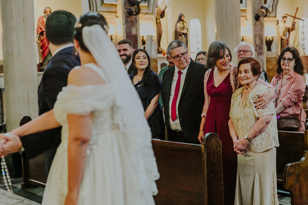 Noivos diante do altar durante a celebração do Sacramento do Matrimônio em casamento católico no Grajaú, Rio de Janeiro. Fotografia de casamento por Aline Lelles do Atelier Fotografia Afetiva