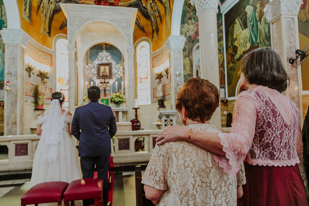 Noivos diante do altar durante a celebração do Sacramento do Matrimônio em casamento católico no Grajaú, Rio de Janeiro. Fotografia de casamento por Aline Lelles do Atelier Fotografia Afetiva