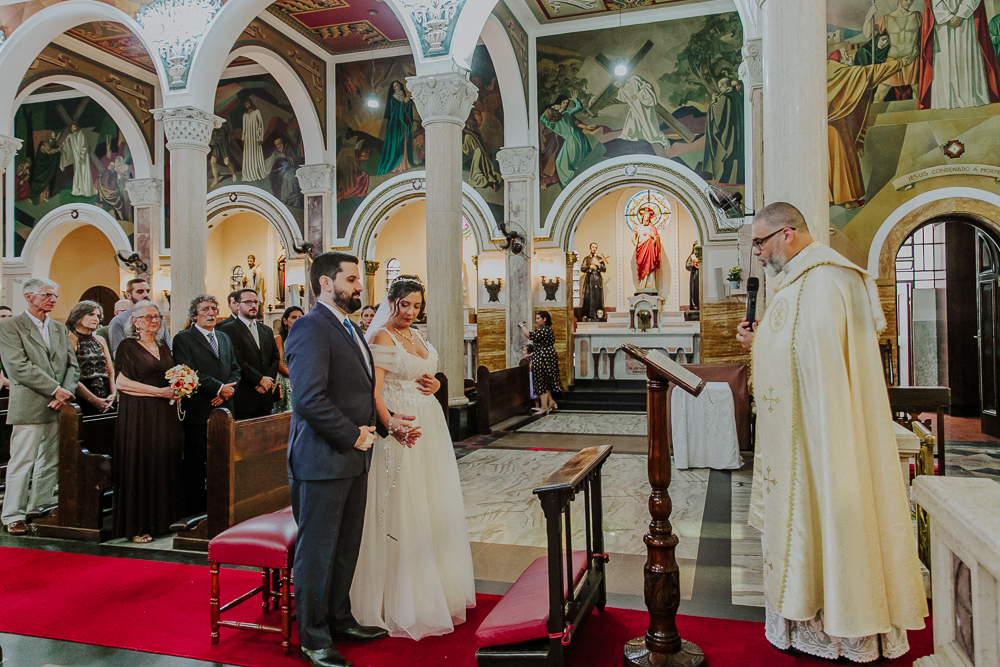 Noivos diante do altar durante a celebração do Sacramento do Matrimônio em casamento católico no Grajaú, Rio de Janeiro. Fotografia de casamento por Aline Lelles do Atelier Fotografia Afetiva
