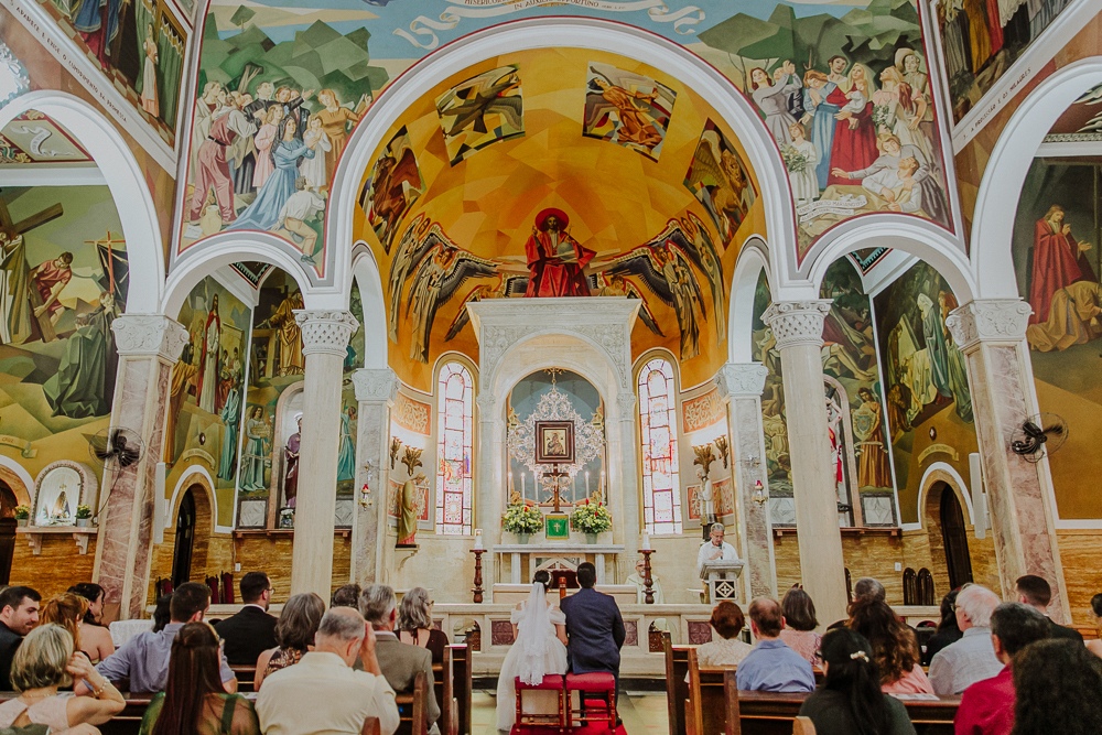 Noivos diante do altar durante a celebração do Sacramento do Matrimônio em casamento católico no Grajaú, Rio de Janeiro. Fotografia de casamento por Aline Lelles do Atelier Fotografia Afetiva