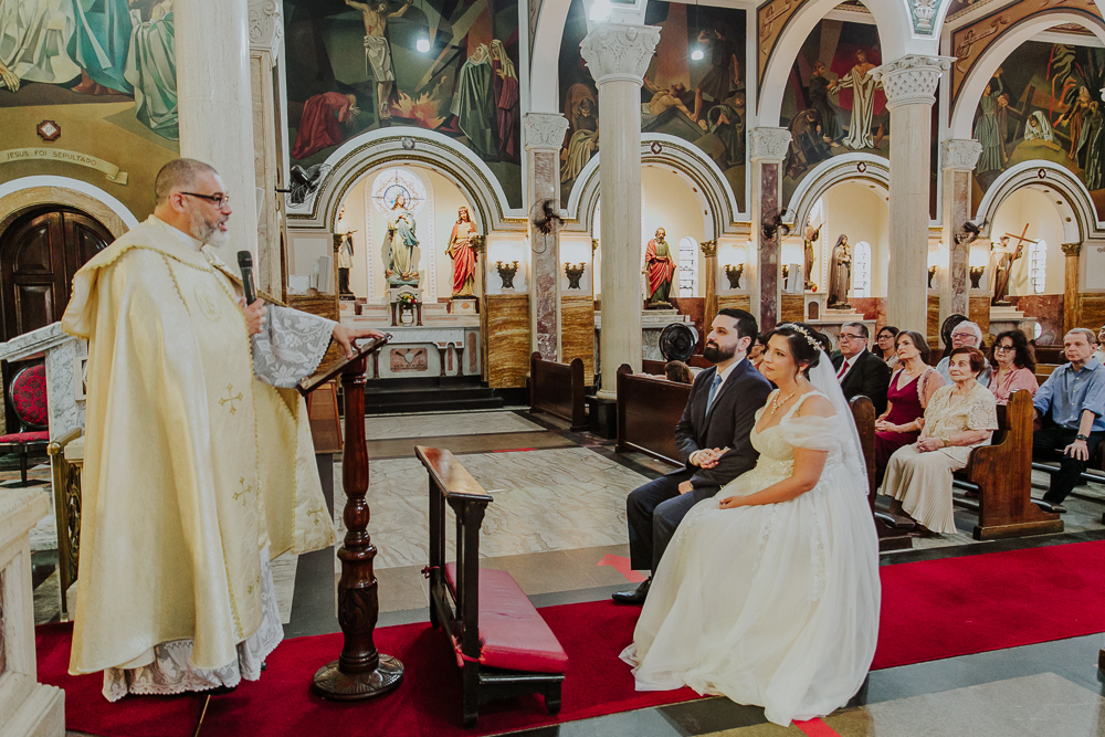 Noivos diante do altar durante a celebração do Sacramento do Matrimônio em casamento católico no Grajaú, Rio de Janeiro. Fotografia de casamento por Aline Lelles do Atelier Fotografia Afetiva