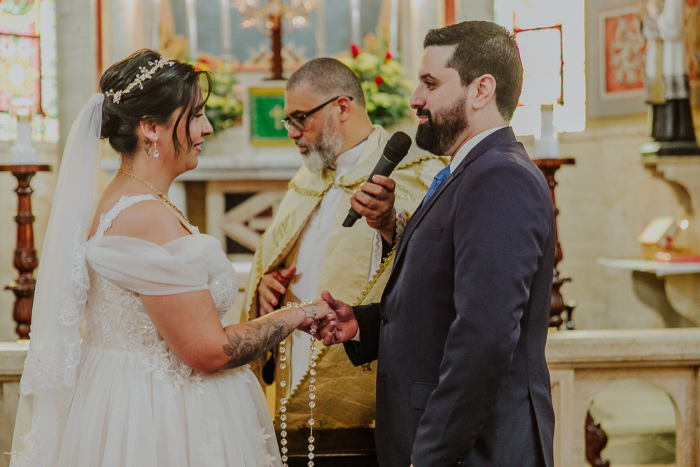 Noivos diante do altar trocando votos durante a celebração do Sacramento do Matrimônio em casamento católico no Grajaú, Rio de Janeiro. Fotografia de casamento por Aline Lelles do Atelier Fotografia Afetiva