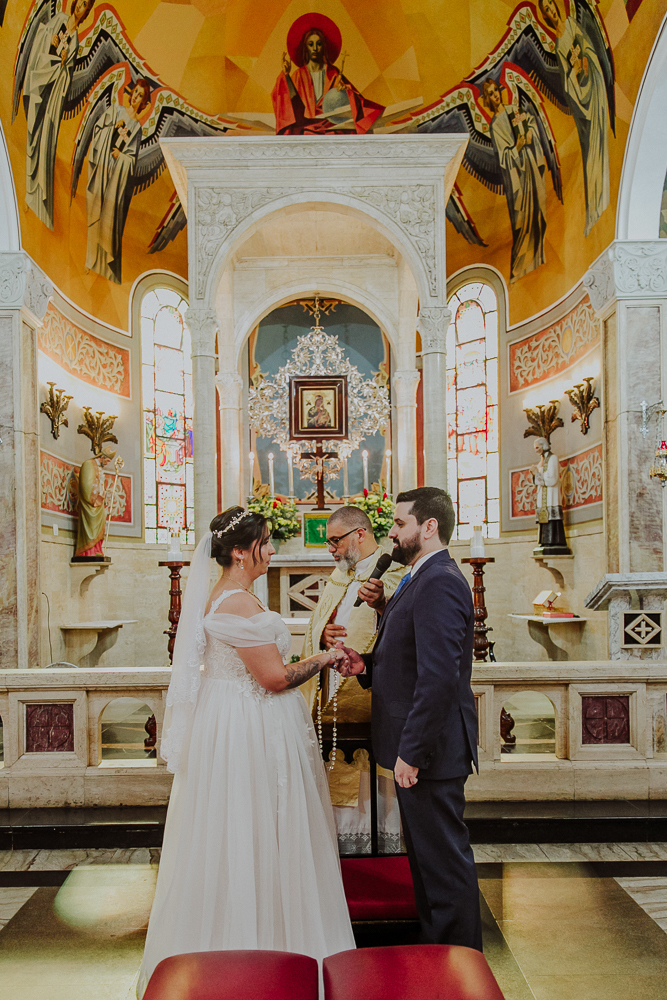 Noivos diante do altar trocando votos durante a celebração do Sacramento do Matrimônio em casamento católico no Grajaú, Rio de Janeiro. Fotografia de casamento por Aline Lelles do Atelier Fotografia Afetiva
