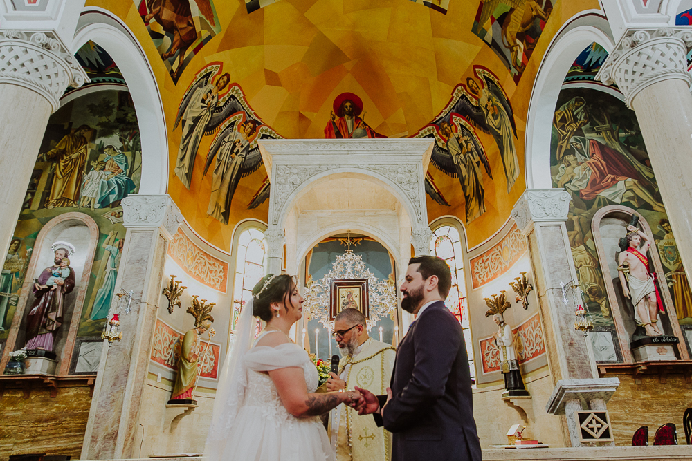 Noivos diante do altar trocando votos durante a celebração do Sacramento do Matrimônio em casamento católico no Grajaú, Rio de Janeiro. Fotografia de casamento por Aline Lelles do Atelier Fotografia Afetiva