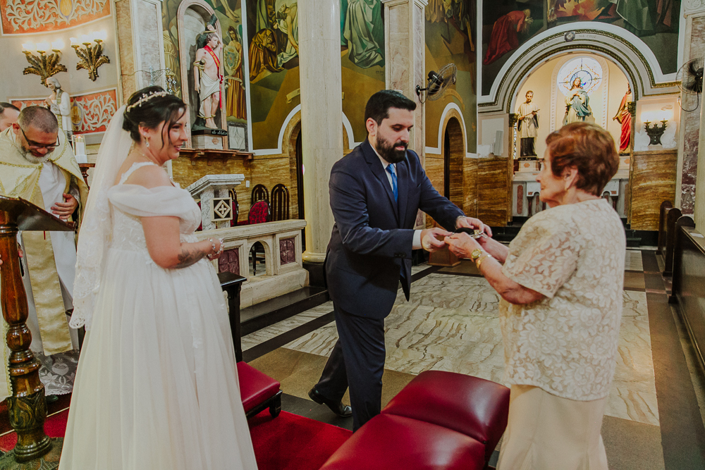 Noivos diante do altar trocando alianças durante a celebração do Sacramento do Matrimônio em casamento católico no Grajaú, Rio de Janeiro. Fotografia de casamento por Aline Lelles do Atelier Fotografia Afetiva