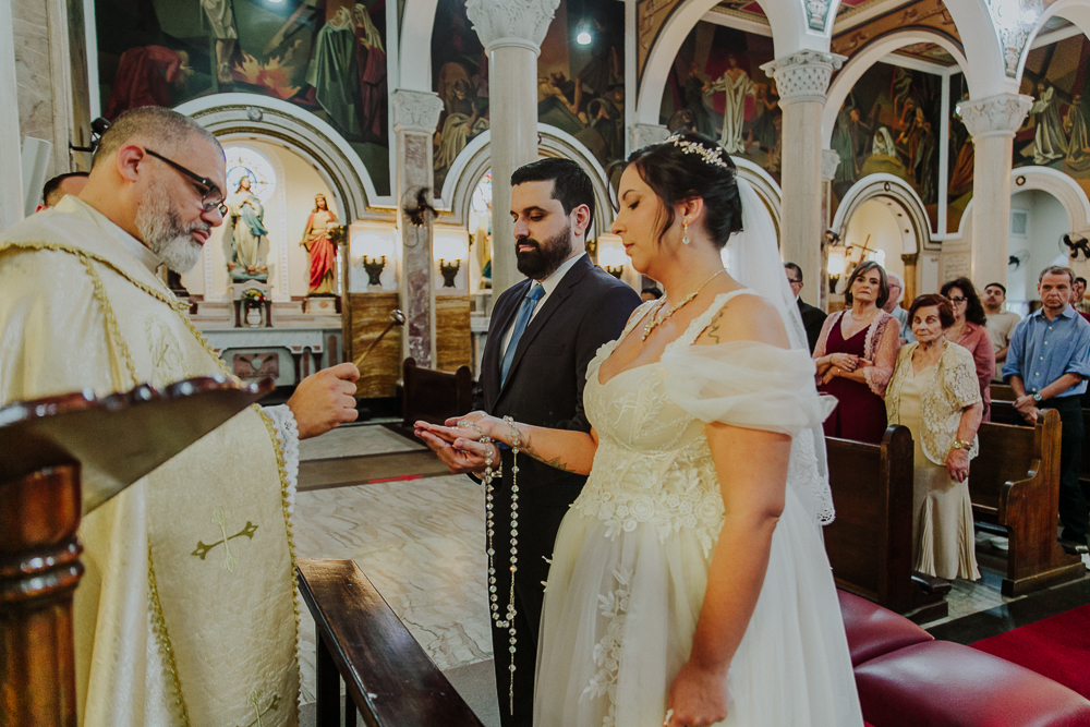 Noivos diante do altar trocando alianças durante a celebração do Sacramento do Matrimônio em casamento católico no Grajaú, Rio de Janeiro. Fotografia de casamento por Aline Lelles do Atelier Fotografia Afetiva