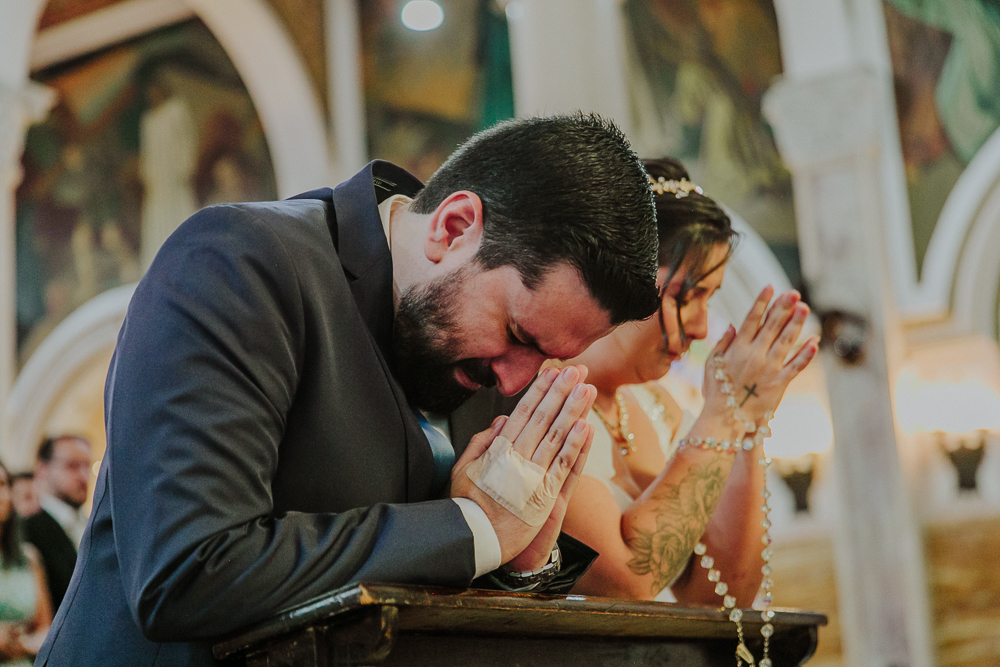 Noivos diante do altar recebendo a Eucaristia durante a celebração do Sacramento do Matrimônio em casamento católico no Grajaú, Rio de Janeiro. Fotografia de casamento por Aline Lelles do Atelier Fotografia Afetiva