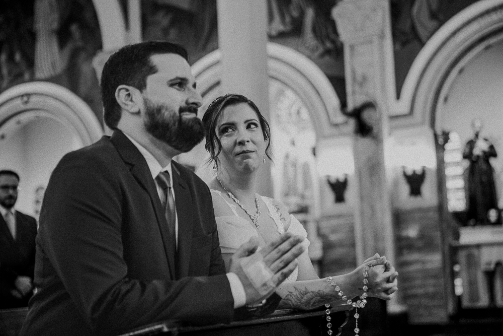 Noivos diante do altar recebendo a Eucaristia durante a celebração do Sacramento do Matrimônio em casamento católico no Grajaú, Rio de Janeiro. Fotografia de casamento por Aline Lelles do Atelier Fotografia Afetiva