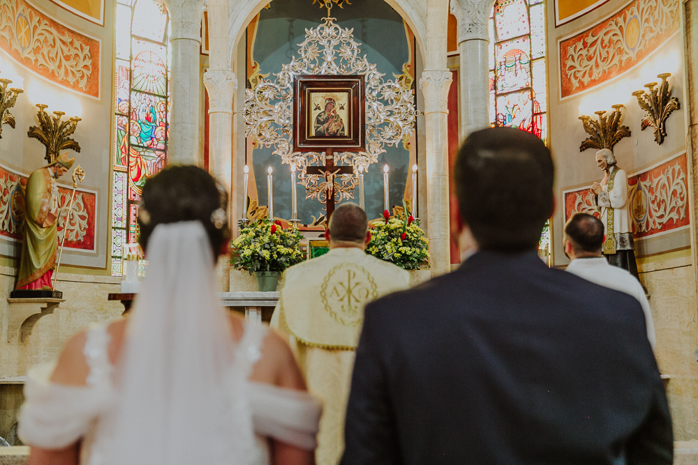 Noivos venerando a imagem de Nossa Senhora do Perpétuo Socorro durante a celebração do Sacramento do Matrimônio em casamento católico no Grajaú, Rio de Janeiro. Fotografia de casamento por Aline Lelles do Atelier Fotografia Afetiva
