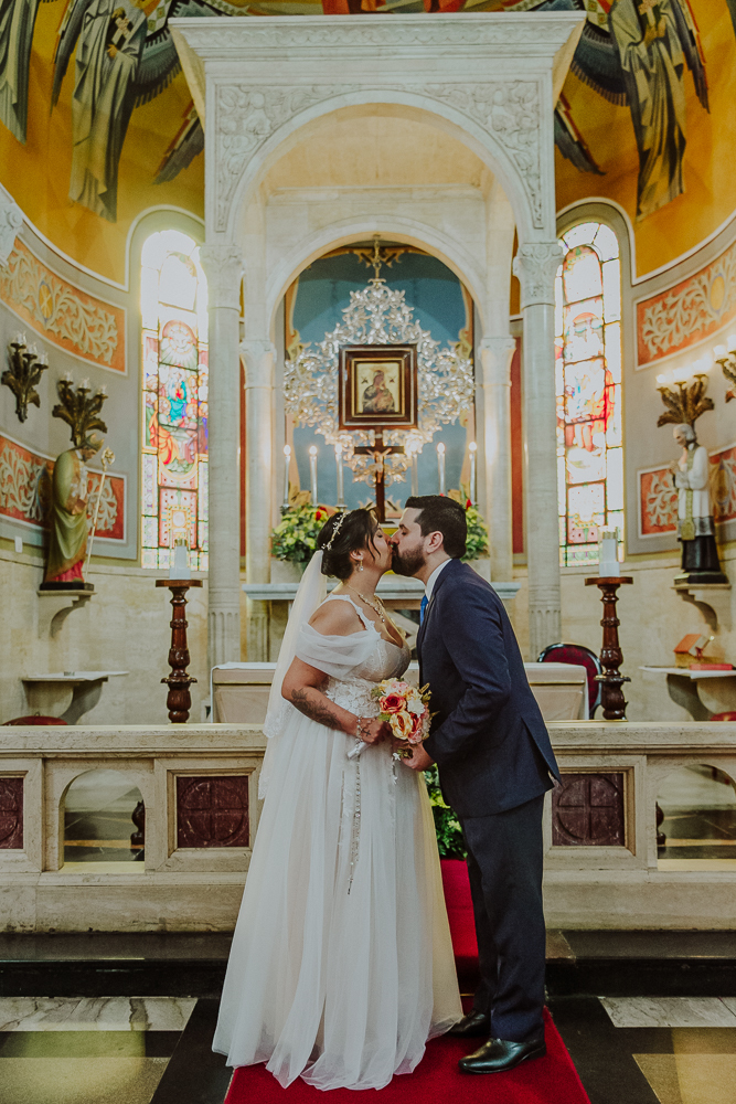 Noivos venerando a imagem de Nossa Senhora do Perpétuo Socorro durante a celebração do Sacramento do Matrimônio em casamento católico no Grajaú, Rio de Janeiro. Fotografia de casamento por Aline Lelles do Atelier Fotografia Afetiva