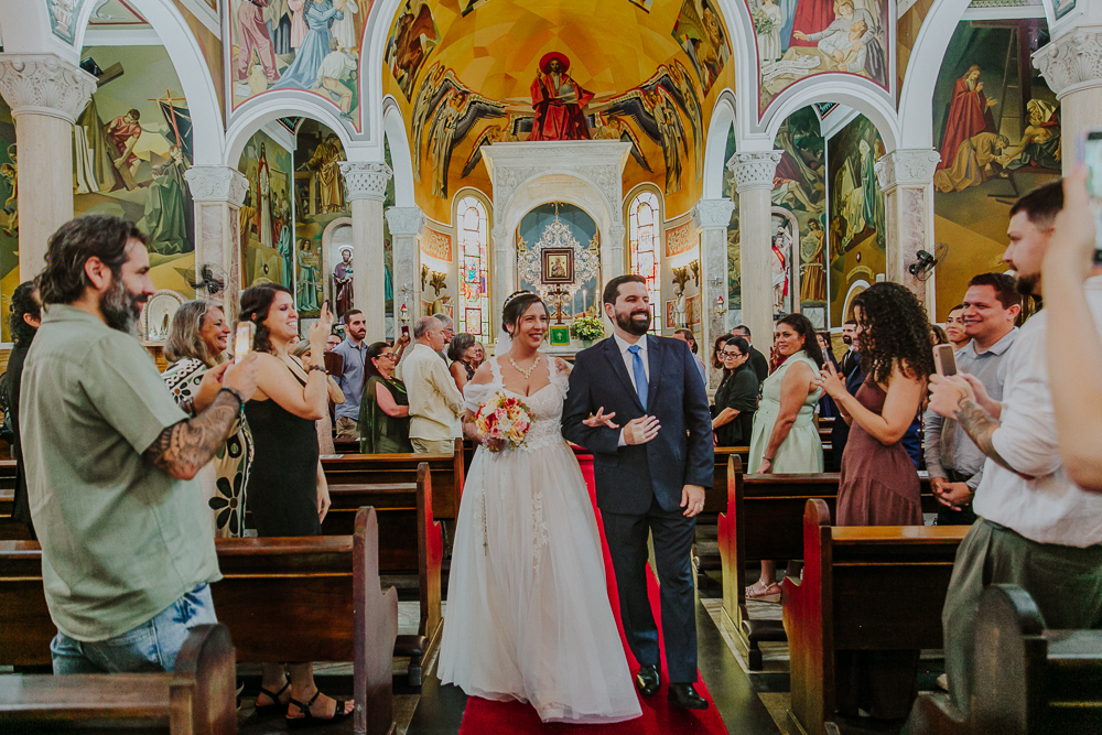 Saída dos noivos na Paróquia Nossa Senhora do Perpétuo Socorro durante a celebração do Sacramento do Matrimônio em casamento católico no Grajaú, Rio de Janeiro. Fotografia de casamento por Aline Lelles do Atelier Fotografia Afetiva