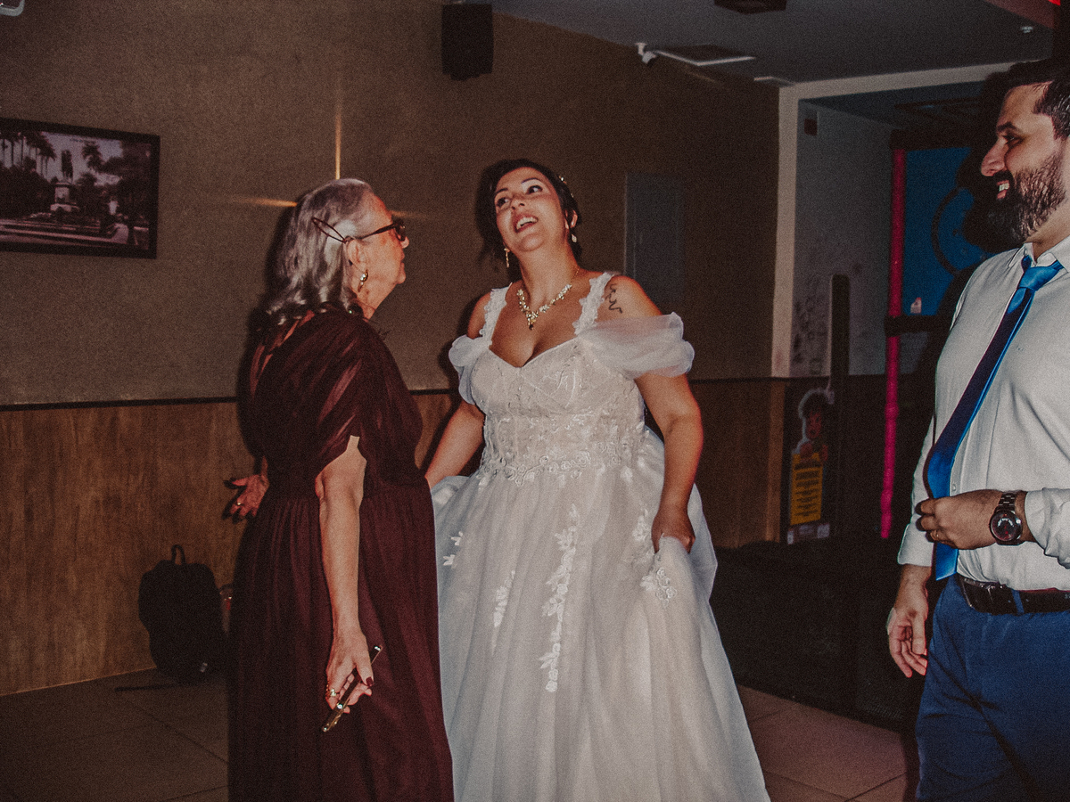 Noivos e convidados dançando na pista em fotografia com flash direto e estética Y2K.