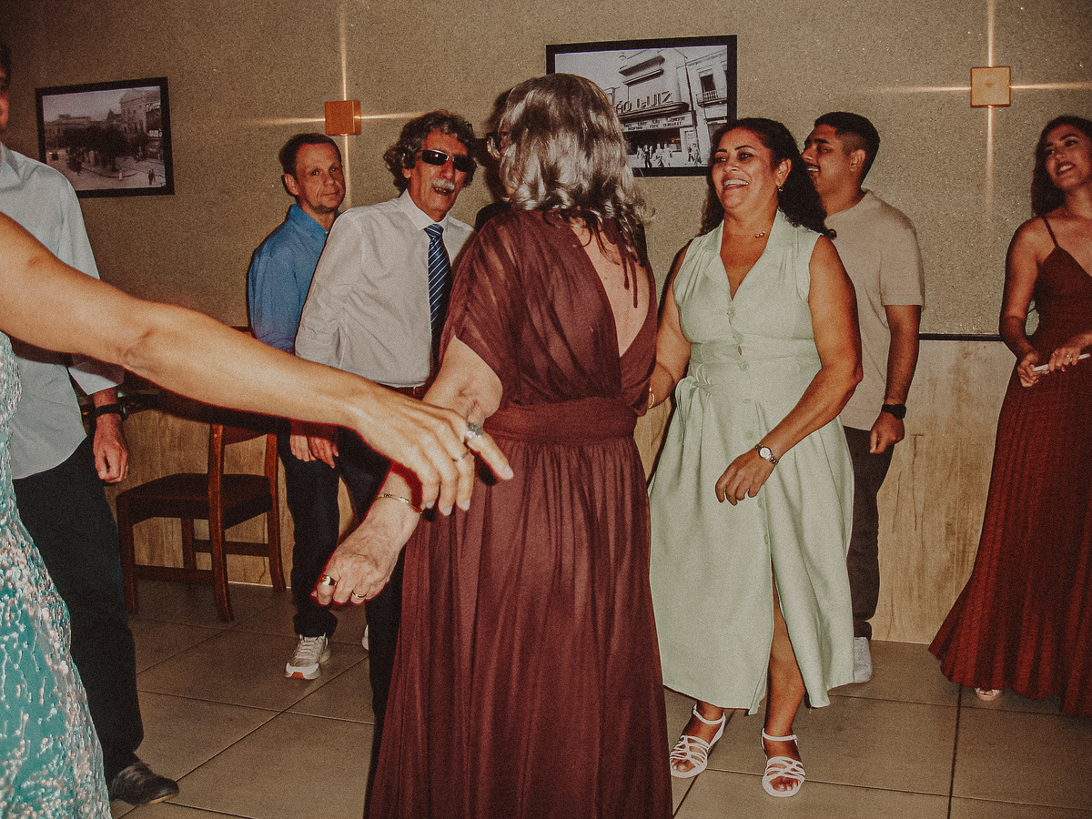 Noivos e convidados dançando na pista em fotografia com flash direto e estética Y2K.