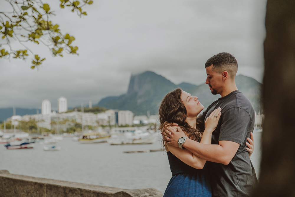 Herberson e Alana se abraçam depois do pedido de casamento surpresa na Mureta da Urca, com a Baía de Guanabara e a paisagem carioca ao fundo.