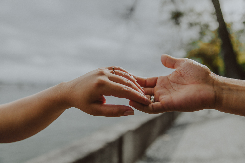 Detalhe das mãos de casal após o pedido de casamento na Urca, destacando a aliança de noivado e a delicadeza do momento.