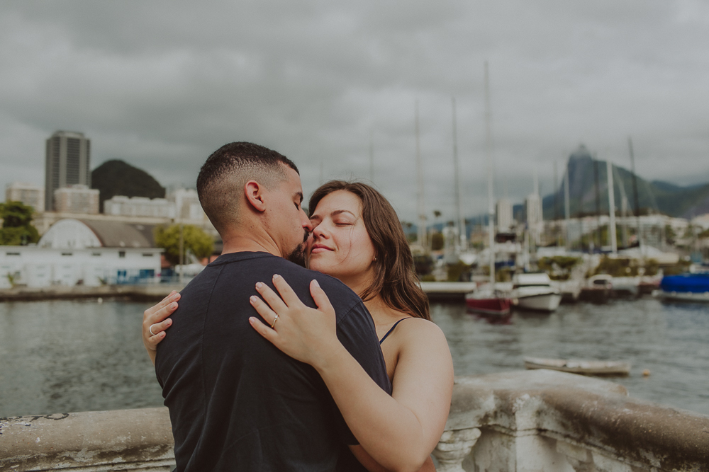 Ensaio de casal de Herberson e Alana na Urca após o pedido de casamento, com a marina e a paisagem do Rio de Janeiro compondo o cenário.
