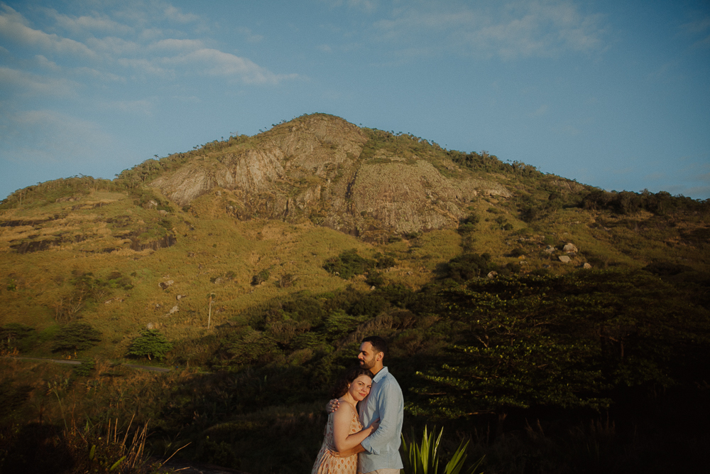 Retrato panorâmico de casal abraçado diante de uma montanha, durante ensaio fotográfico na Praia do Secreto RJ.