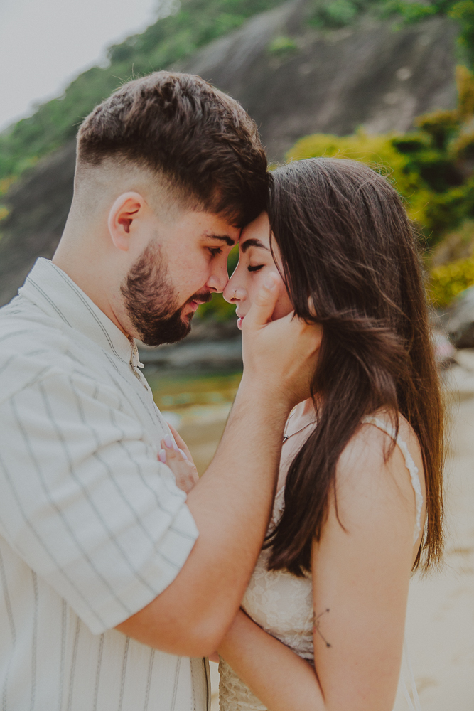 Retrato afetivo de Gabriel e Júlia com os rostos próximos, durante o ensaio de casal na Praia Vermelha, Urca, Rio de Janeiro.