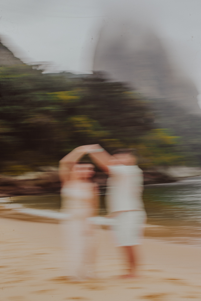 Gabriel conduz Júlia em uma dança espontânea à beira-mar, em fotografia com movimento durante o ensaio na Praia Vermelha, RJ. Fotografia desfocada é arte. Baixa velocidade obturador camera fotografica