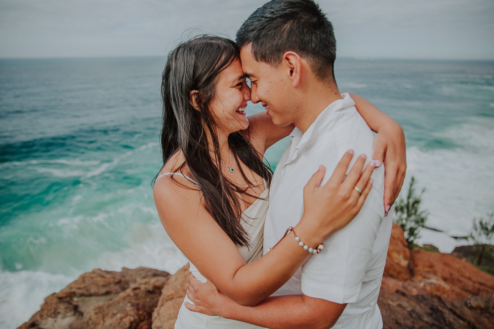 Diego y María sonríen con las frentes juntas durante su sesión fotográfica de pareja en el Mirante da Joatinga.