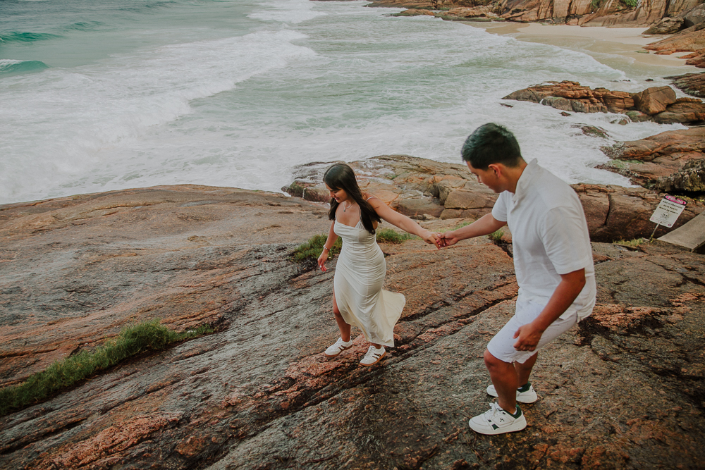 Diego ayuda a María a caminar de la mano sobre las rocas junto al mar, durante su sesión de fotos en Río de Janeiro.