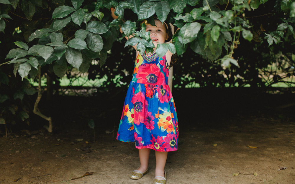 menina escondida fazendo travessura durante ensaio fotografico no jardim botanico do rio de janeiro