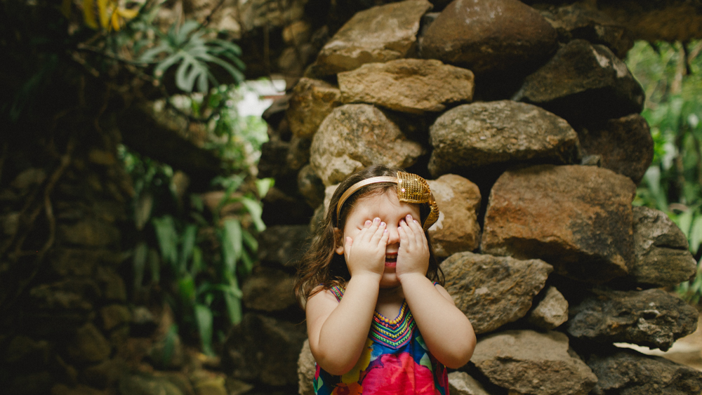 m&atilde;e e filha se divertem brincando de pique-esconde durante ensaio fotogr&aacute;fico de fam&iacute;lia no jardim bot&acirc;nico do rio de janeiro