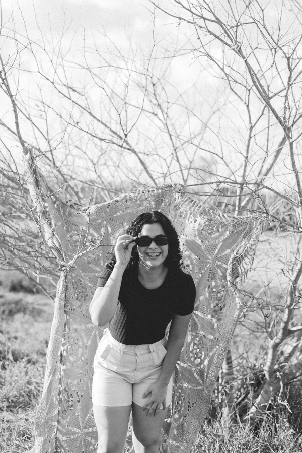 ensaio feminino externo com arvores e oculos escuro sorrindo