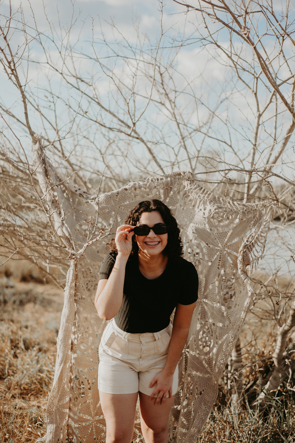 ensaio feminino externo com arvores e oculos escuro sorrindo