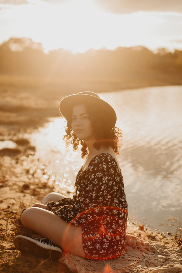 ensaio feminino externo a beira do lago com roupa preta e branca e chapeu marron estilo boho, menina cacheada
