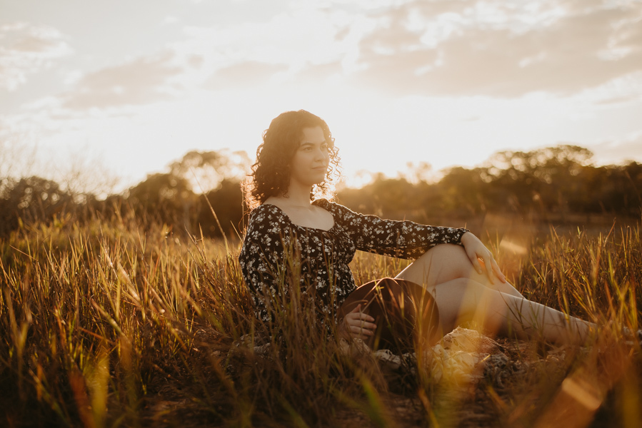 ensaio feminino externo a beira do lago com roupa preta e branca e chapeu marron estilo boho, menina cacheada. fotos no por do sol, 
