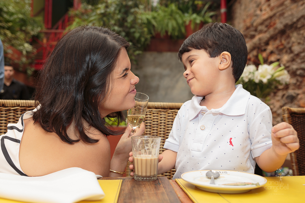 foto da mãe com o filho fazendo brinde. Ela com uma taça e ele com um copinho de leite.
