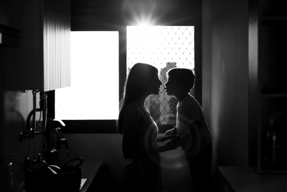 Silhueta de mãe e filho abraçados, com a luz dourada do pôr do sol ao fundo, simbolizando amor e segurança.
