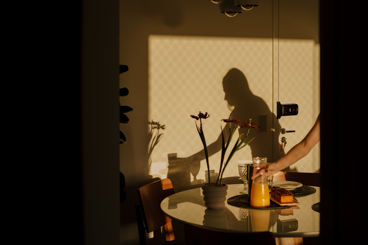 Sombras na parede mostram a interação entre mãe e filho, criando um retrato emotivo de sua relação através da luz e da sombra.