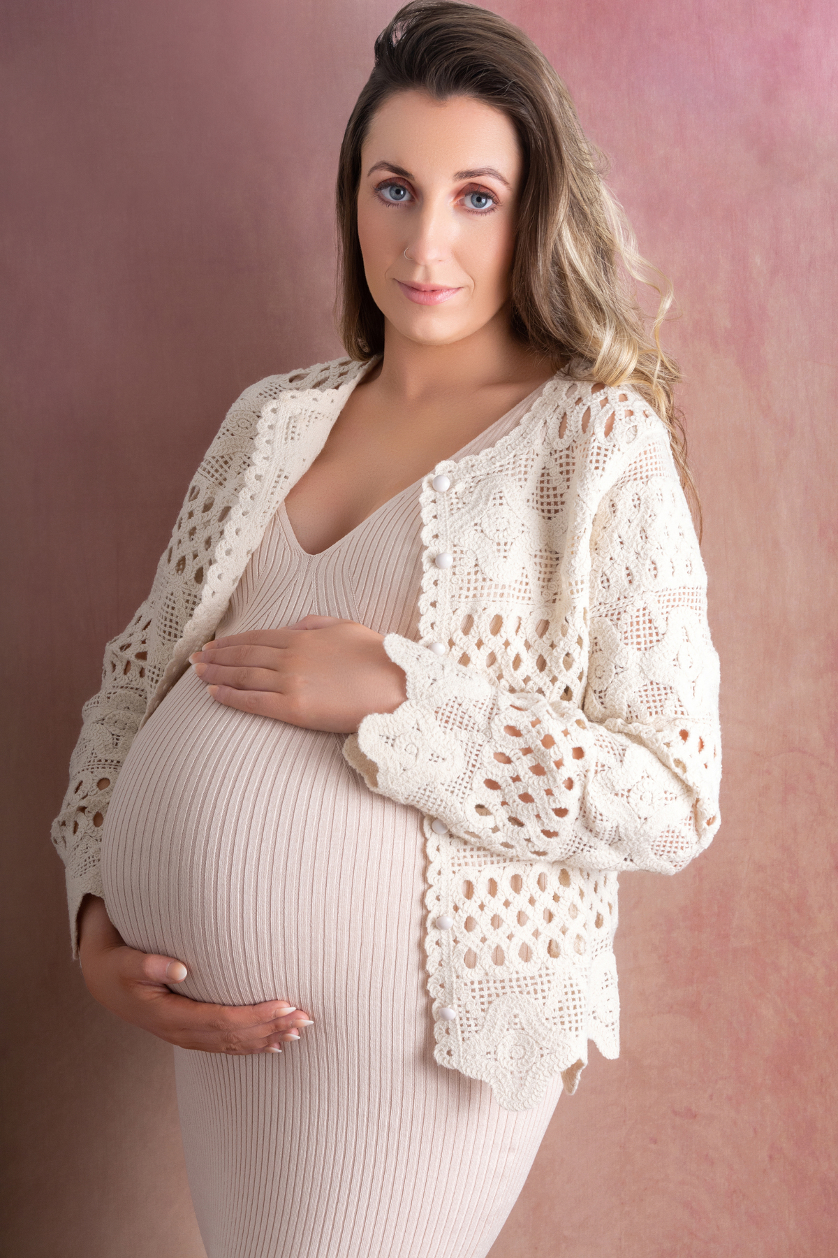 mum to be holding her belly bump looking or rhe camera