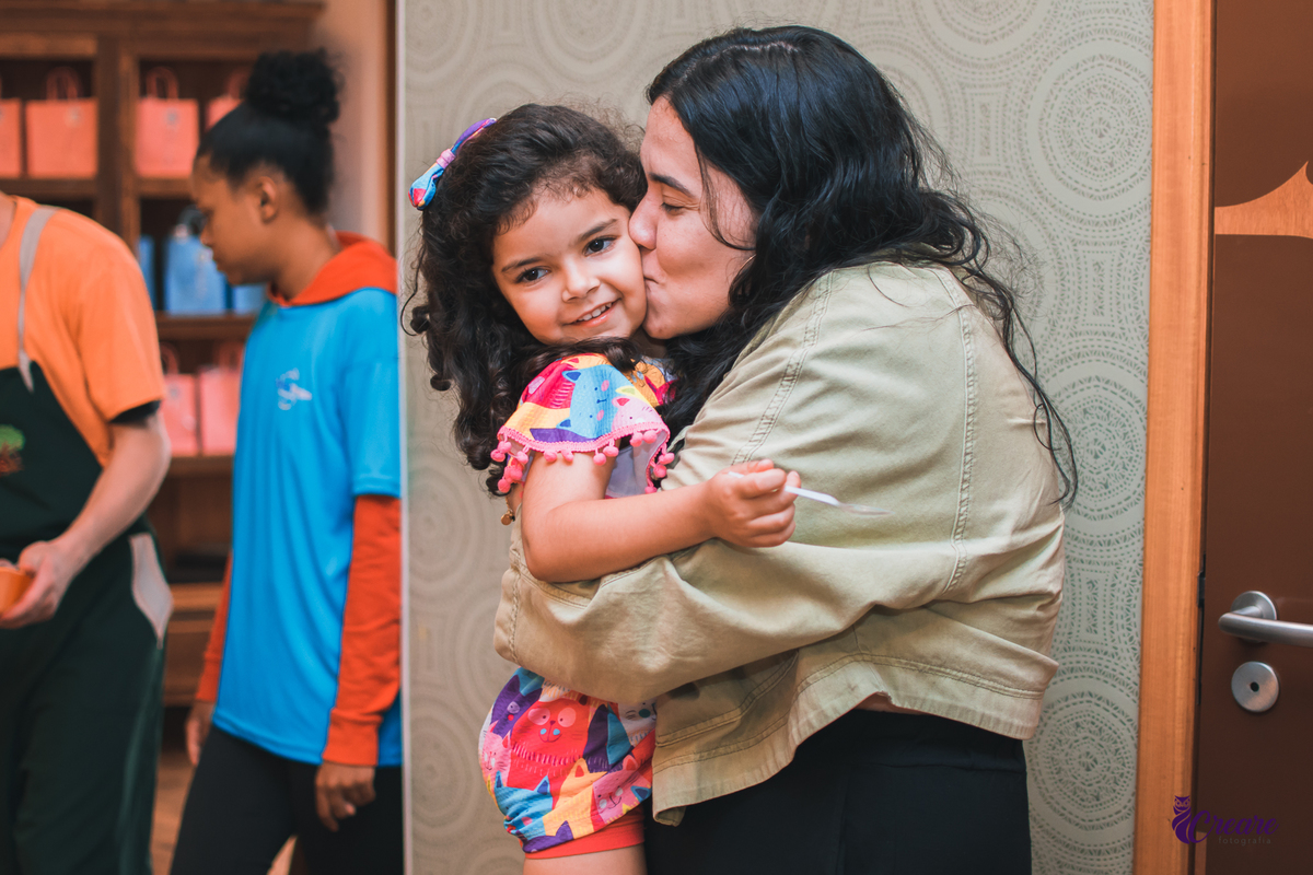 aniversário infantil, festa de menina com tema casa mágica de Gabby. festa realizada no buffet Quintal das Aroeiras em Santo André, ABC Paulista. imagem contém: uma garotinha de 4 anos, recebendo um beijo de uma mulher jovem com jaqueta verde.