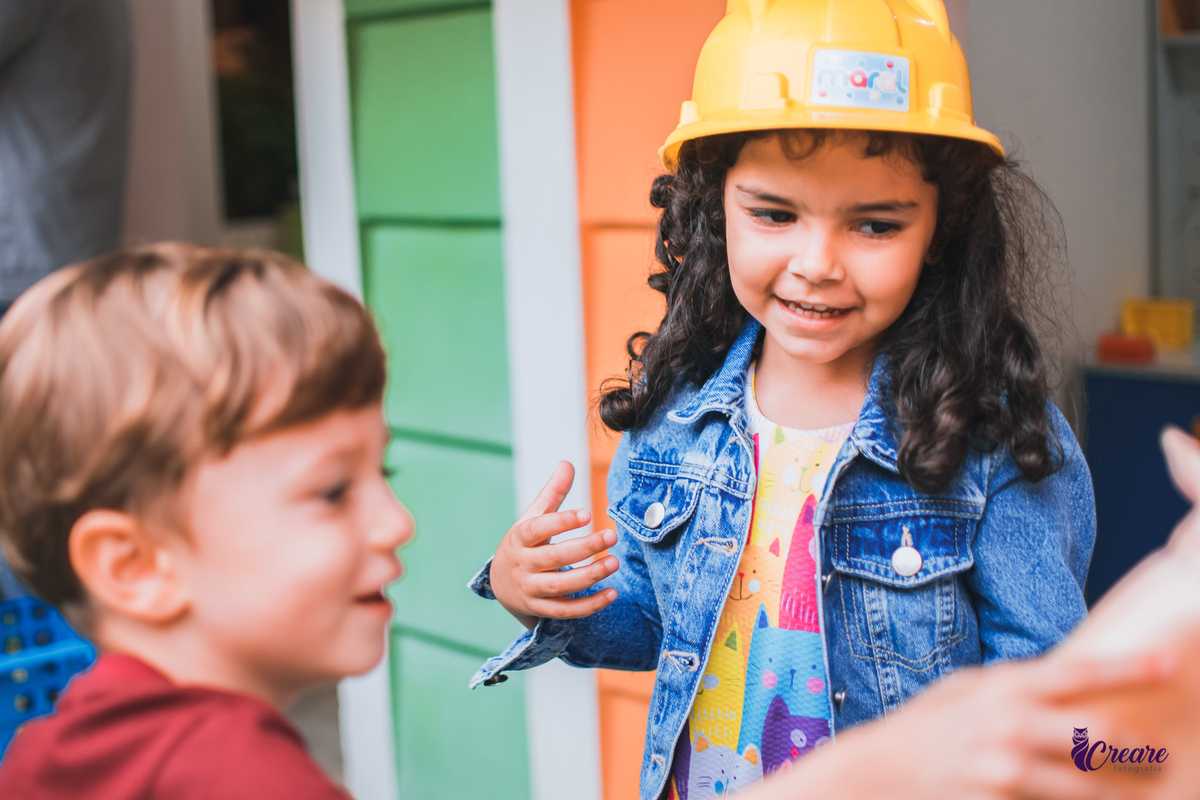 aniversário infantil, festa de menina com tema casa mágica de Gabby. festa realizada no buffet Quintal das Aroeiras em Santo André, ABC Paulista. imagem contém: criança de cabelos cacheados e preto, de jaqueta azul e vestido colorido  e chapeu amarelo