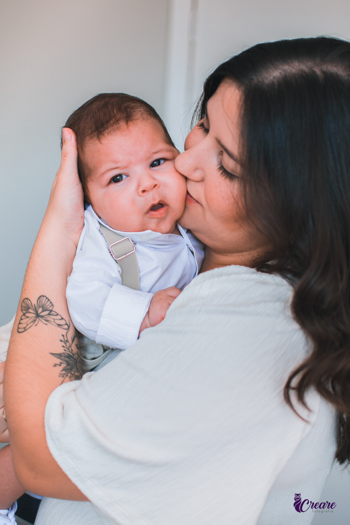 Ensaio newborn lifestyle, ensaio família. A imagem contém: um homem jovem com roupa branca, uma mulher jovem com roupa branca, um bebê com roupa branca e bermuda bege com suspensório. fotógrafo Mauá, ensaio lifestyle. 