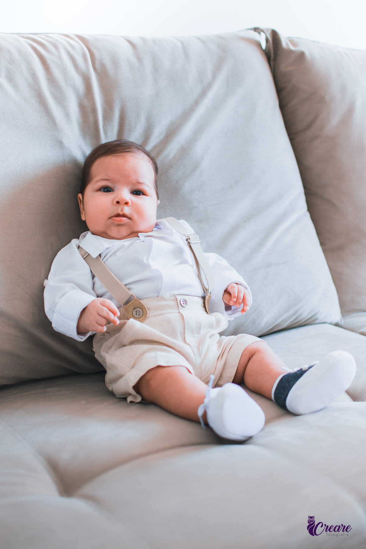 Ensaio newborn lifestyle, ensaio família. A imagem contém: um homem jovem com roupa branca, uma mulher jovem com roupa branca, um bebê com roupa branca e bermuda bege com suspensório. fotógrafo Mauá, ensaio lifestyle. 