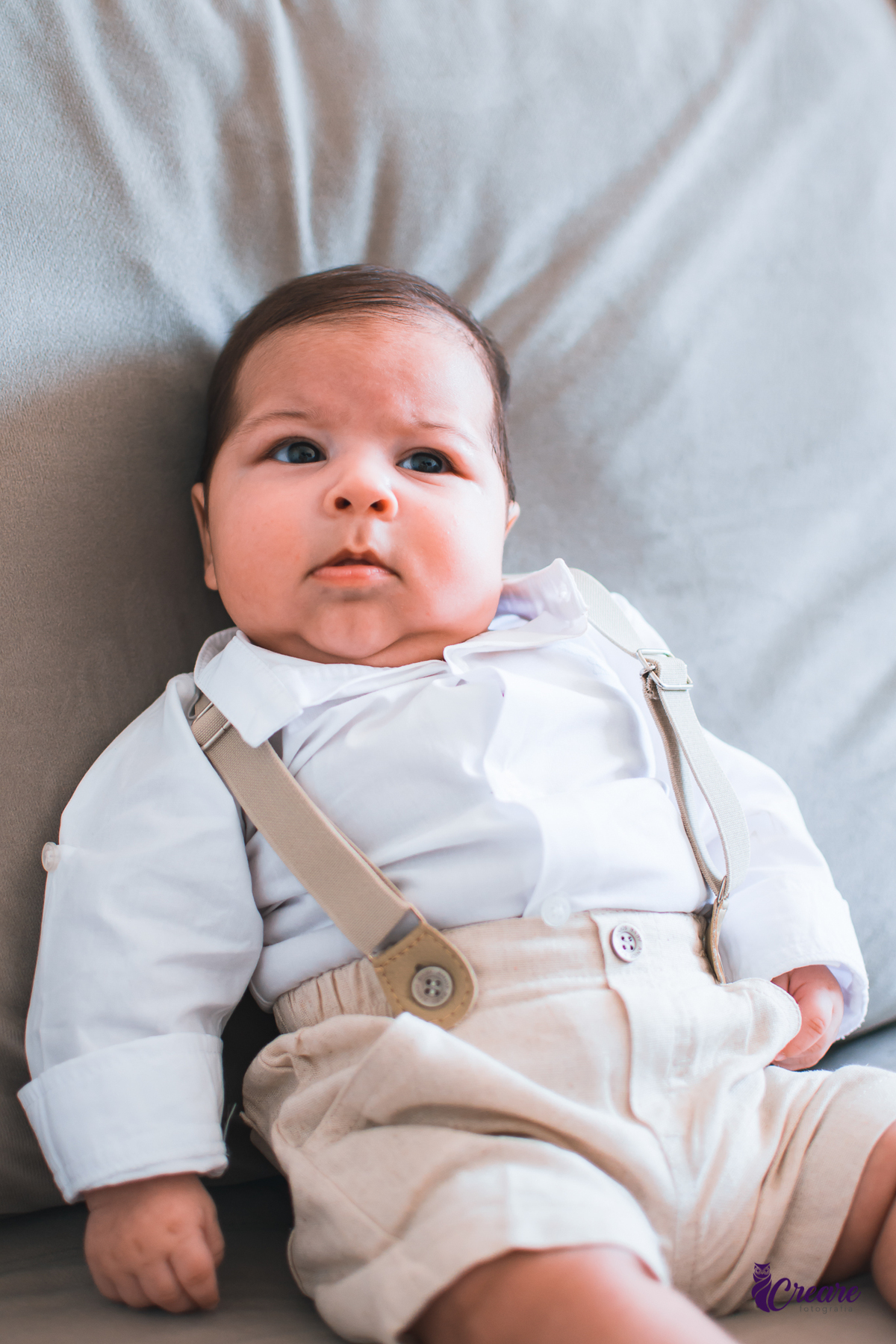 Ensaio newborn lifestyle, ensaio família. A imagem contém: um homem jovem com roupa branca, uma mulher jovem com roupa branca, um bebê com roupa branca e bermuda bege com suspensório. fotógrafo Mauá, ensaio lifestyle. 