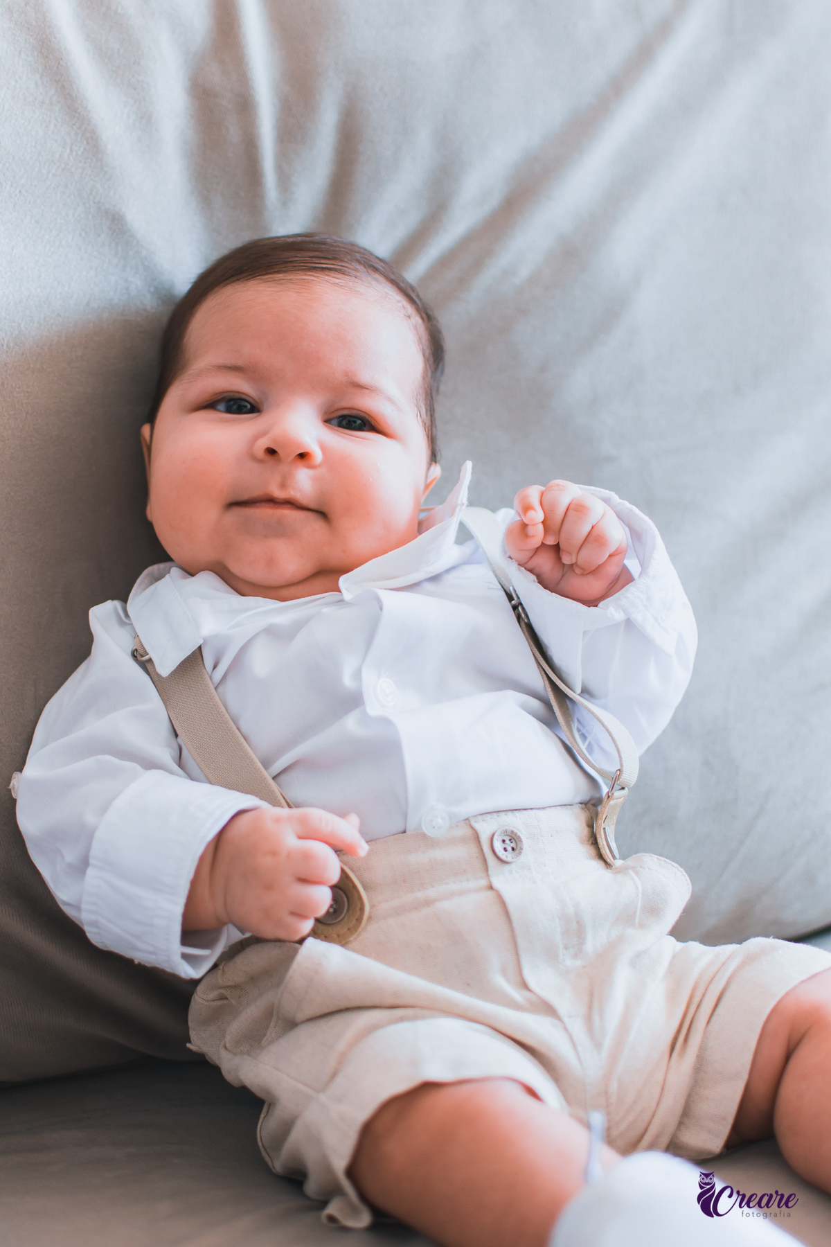 Ensaio newborn lifestyle, ensaio família. A imagem contém: um homem jovem com roupa branca, uma mulher jovem com roupa branca, um bebê com roupa branca e bermuda bege com suspensório. fotógrafo Mauá, ensaio lifestyle. 