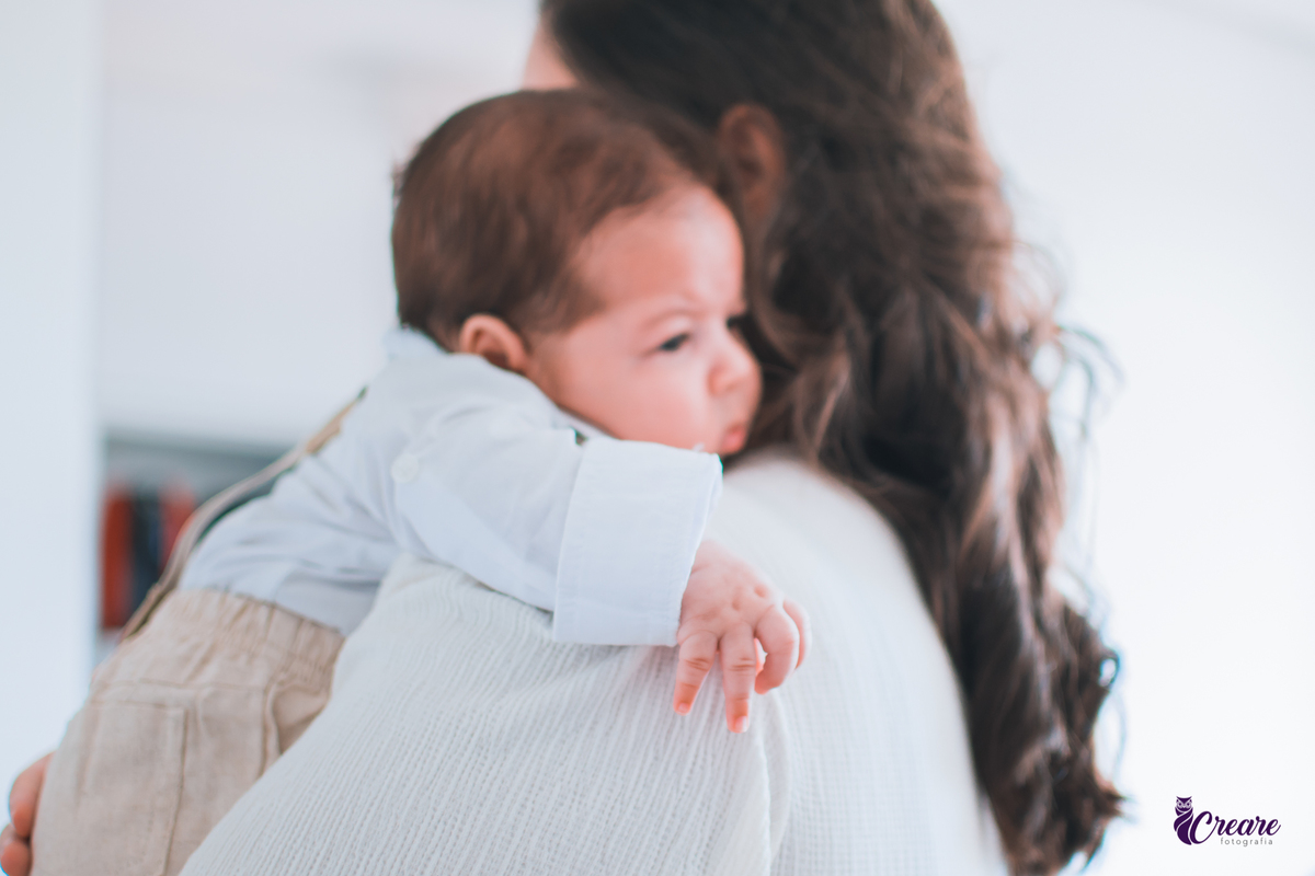 Ensaio newborn lifestyle, ensaio família. A imagem contém: um homem jovem com roupa branca, uma mulher jovem com roupa branca, um bebê com roupa branca e bermuda bege com suspensório. fotógrafo Mauá, ensaio lifestyle. 