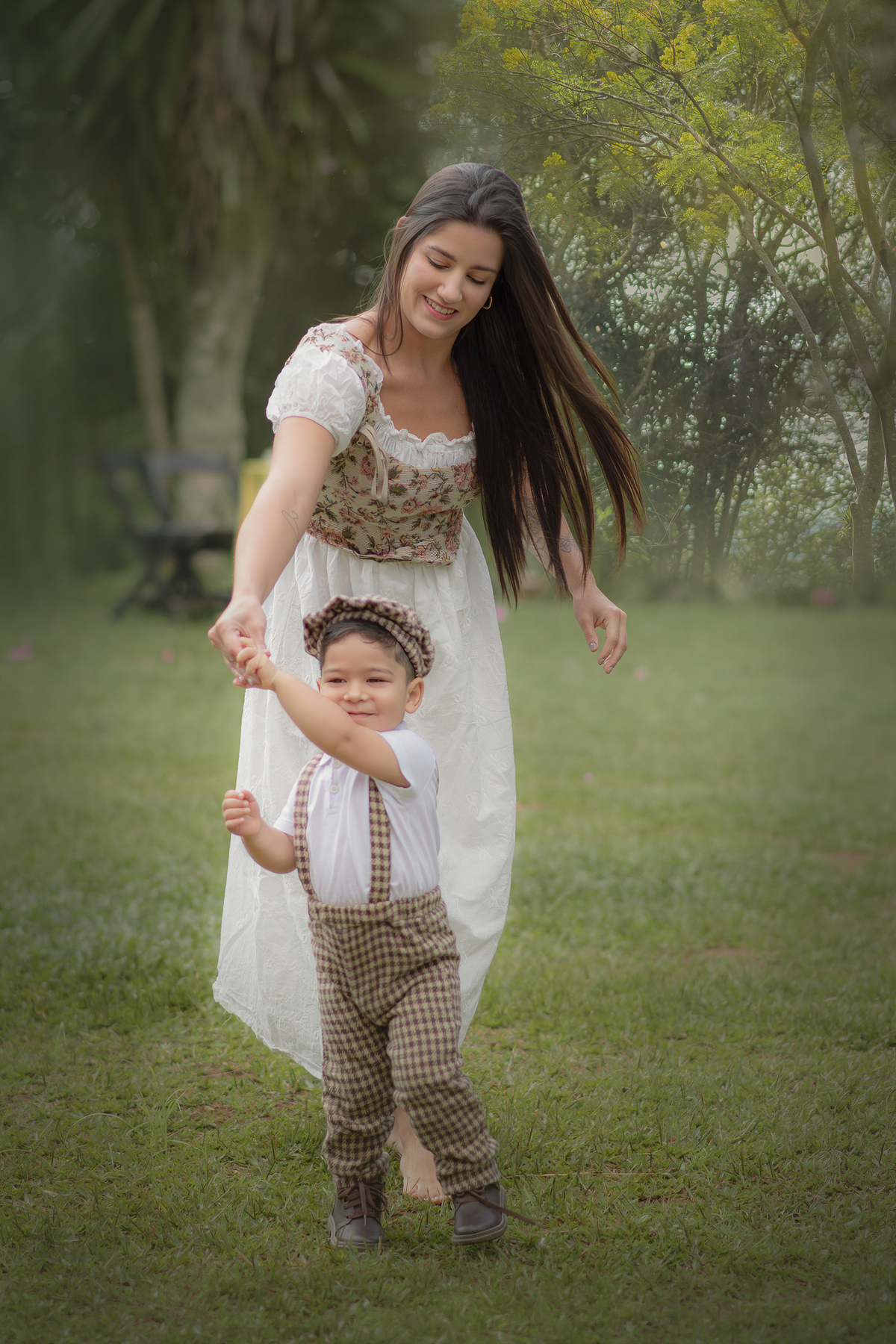 Uma mulher e uma criança, brincando de rodar em um parque, durante o ensaio fotográfico de dia das mães ao ar livre.