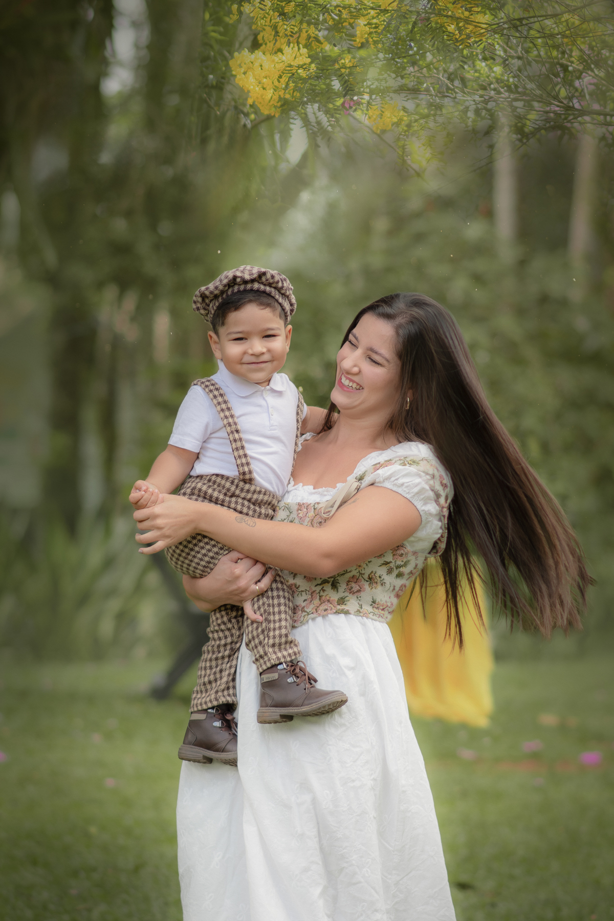 Uma mulher e uma criança no colo, brincando de rodar em um parque, durante o ensaio fotográfico de dia das mães ao ar livre.