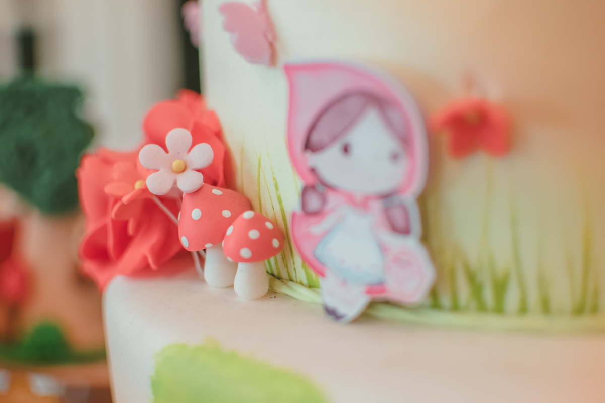 detalhes da decoração de um bolo de aniversário com tema chápeuzinho vermelho.