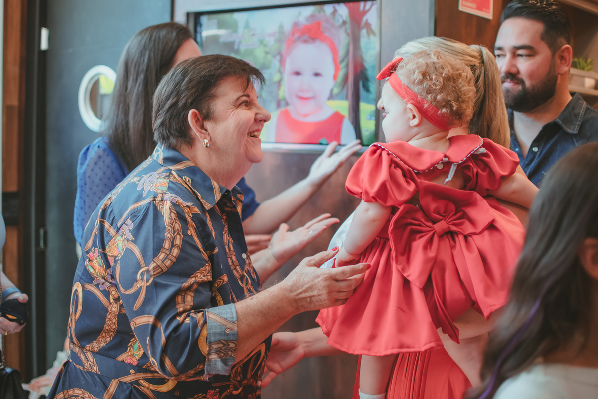 Uma mulher de idade sorrindo para uma bebê durante a festa de aniversário de um ano dela.